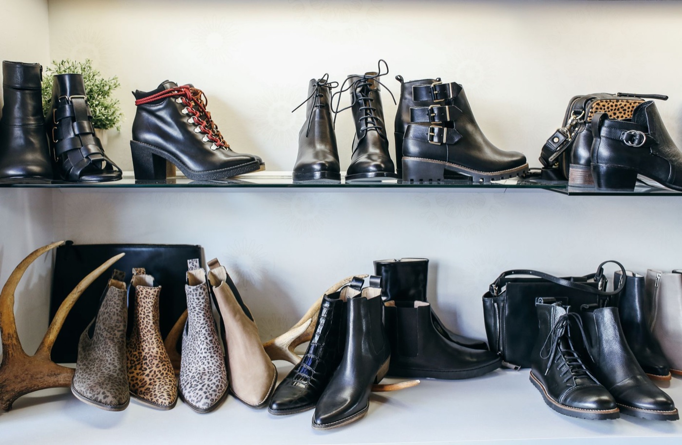 Two glass shelves in a boutique lined with black and leopard-print ankle boots