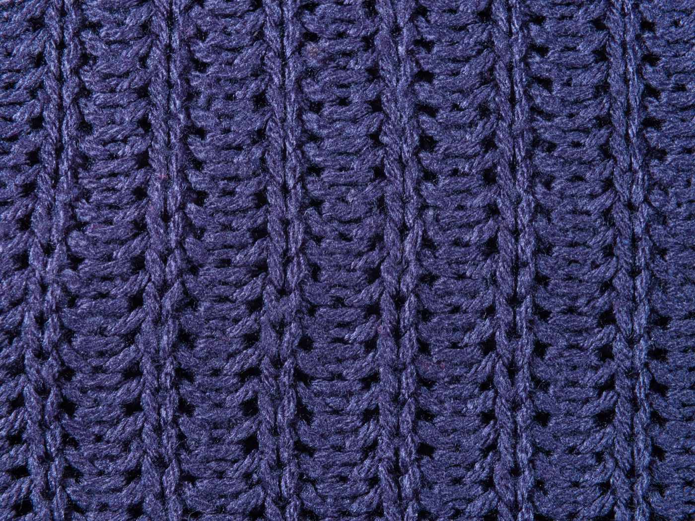 Macro photograph of a navy ribbed knit, individual twisted yarn strands and the gaps between stitches clearly visible