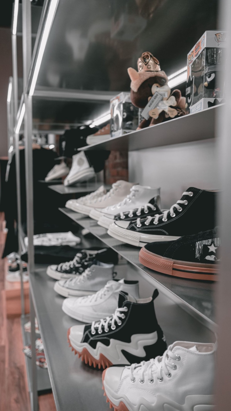 Metal retail shelves lined with rows of high-top and low-top sneakers in a dim shop