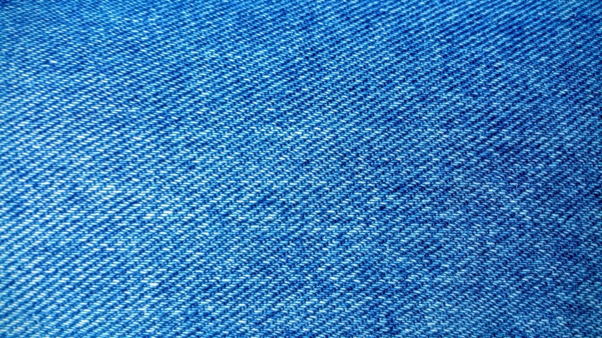 Extreme close-up of blue denim twill weave with white weft threads showing through the indigo surface