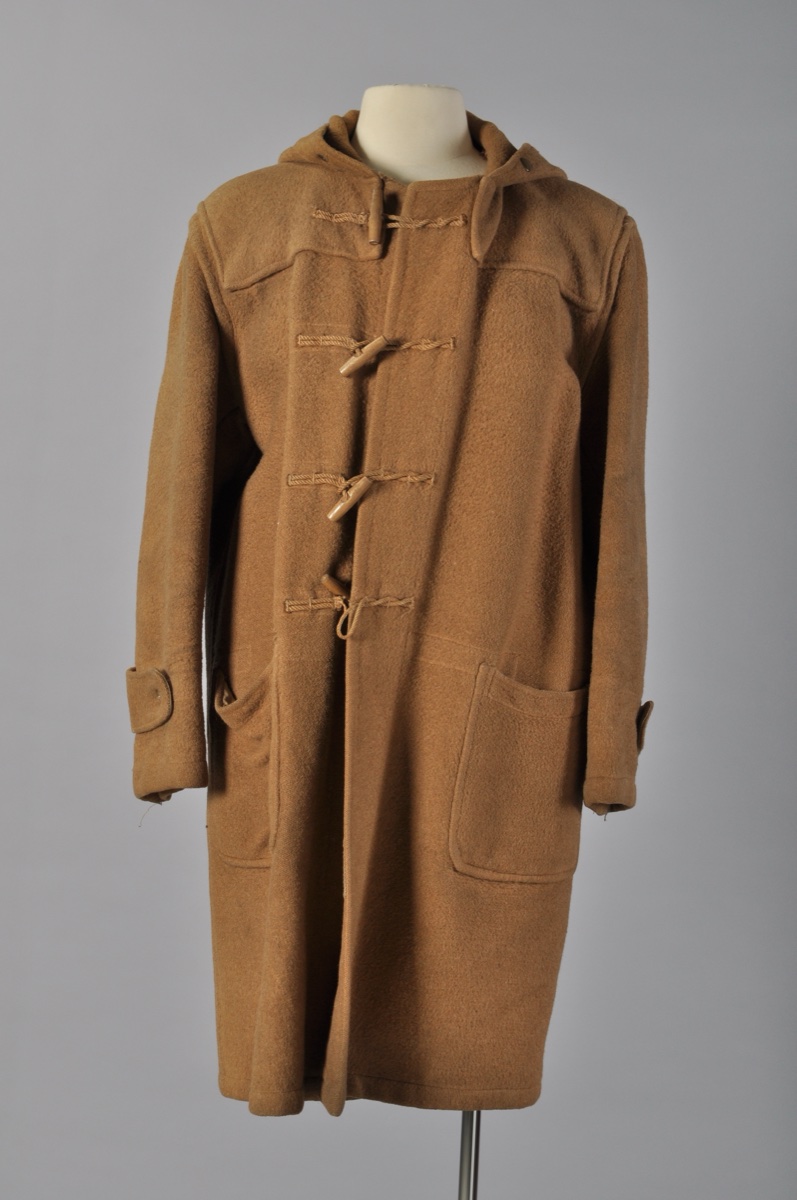 A vintage camel monty coat with rope-and-toggle closures and patch pockets displayed on a mannequin against a grey studio backdrop