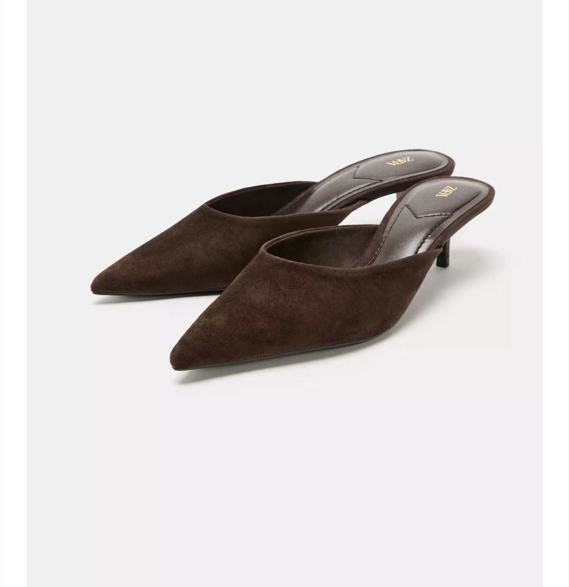 A pair of brown suede pointed-toe kitten-heel mules with the Zara logo on the insole, on a plain light background