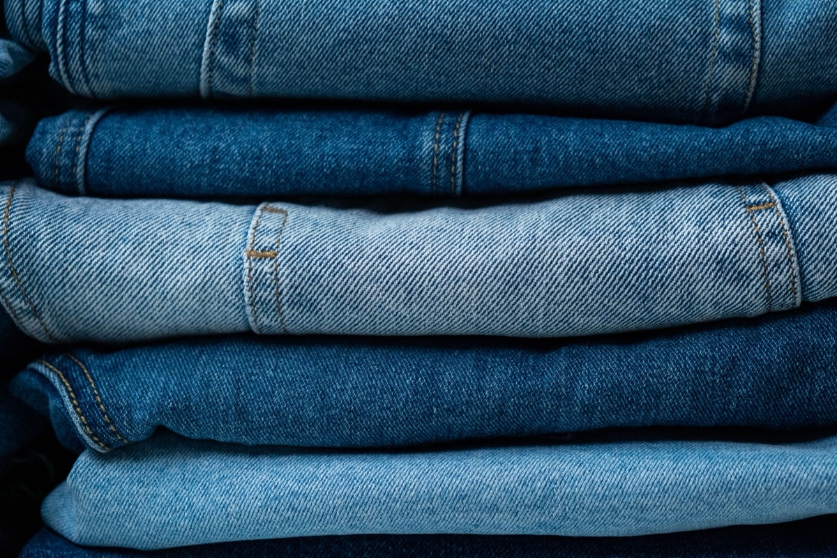 Close-up of five pairs of folded jeans stacked, washes alternating light and dark