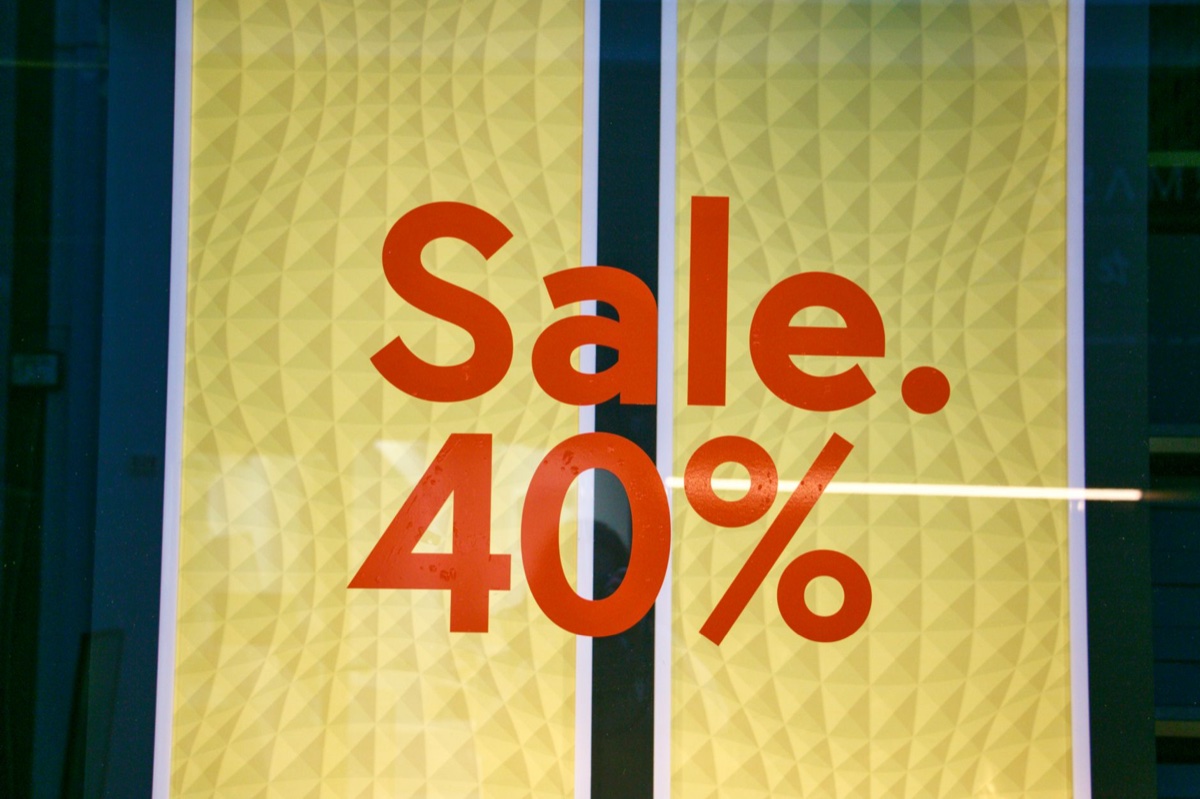 A shop window covered in yellow vinyl with the words Sale and 40 percent printed across it in red
