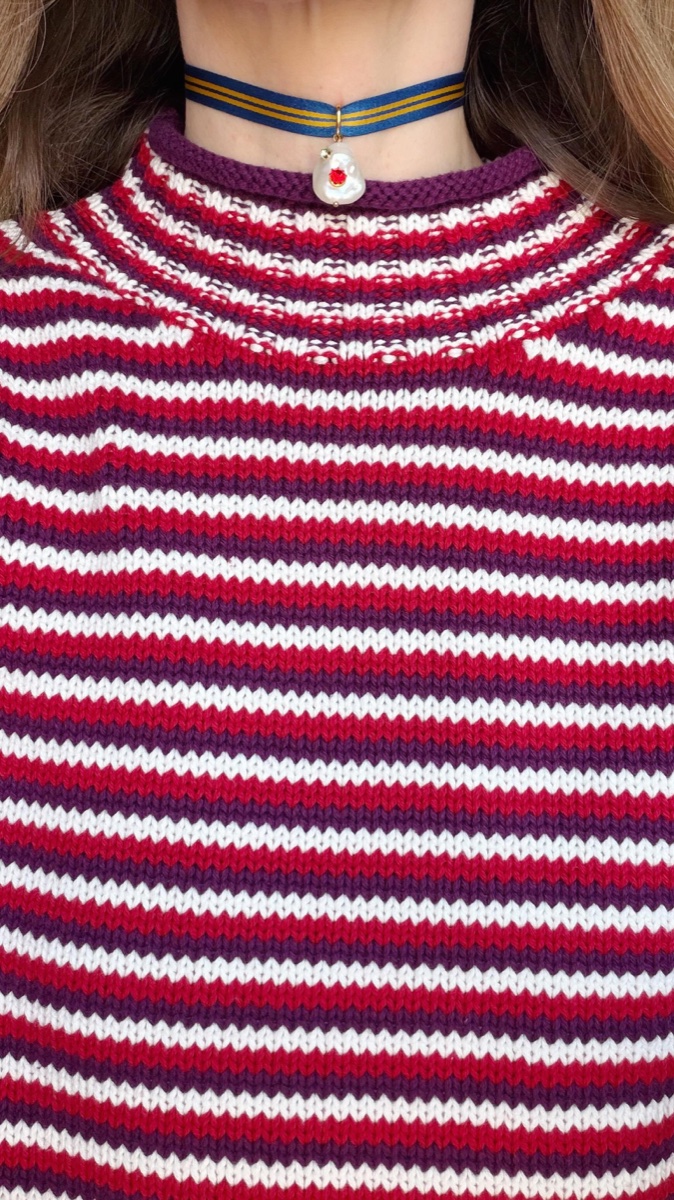 Close-up of the rolled, unfinished collar on a red, white and purple striped J.Crew rollneck sweater