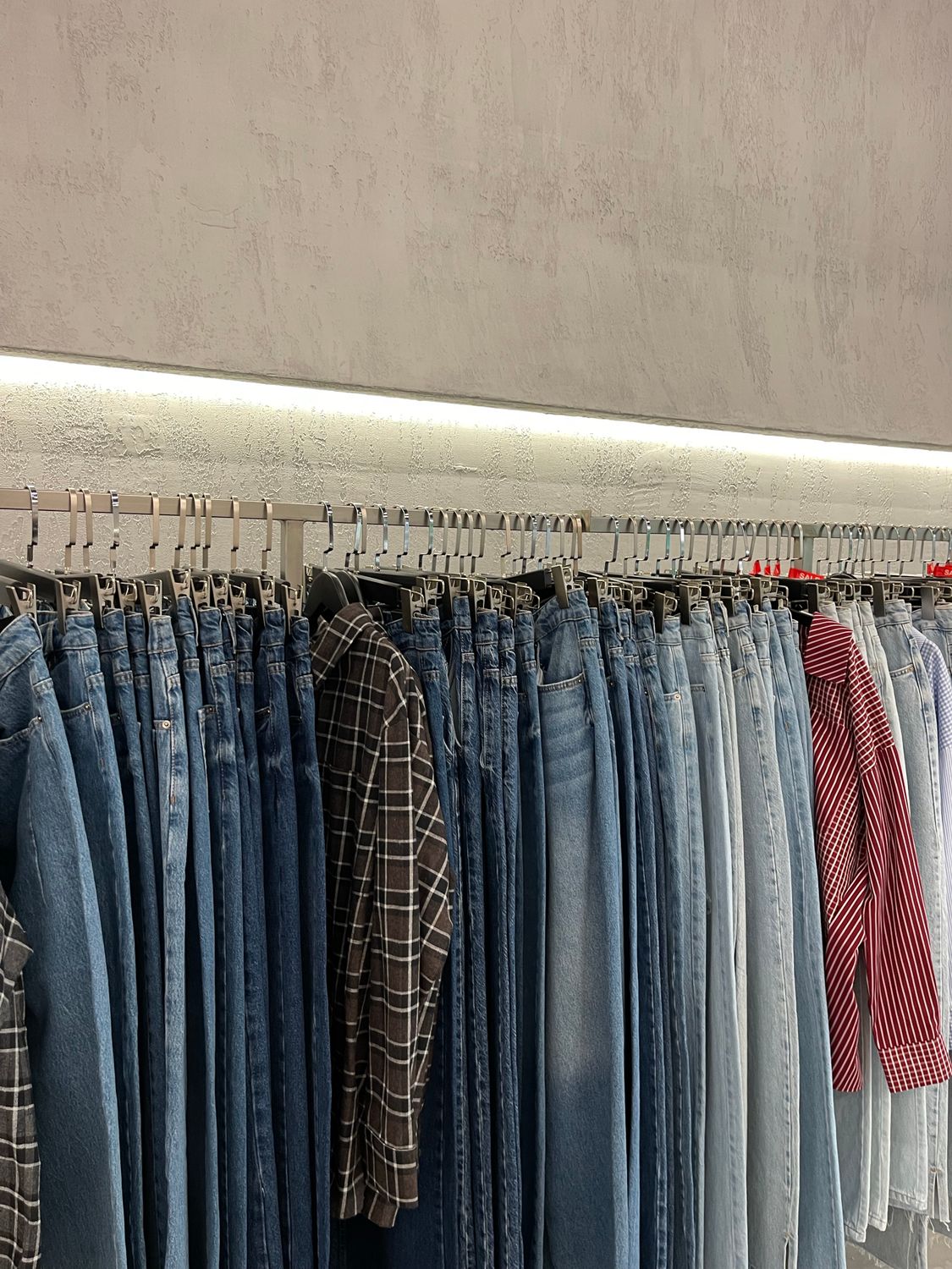 Jeans and shirts hanging on a rail in a modern clothing store