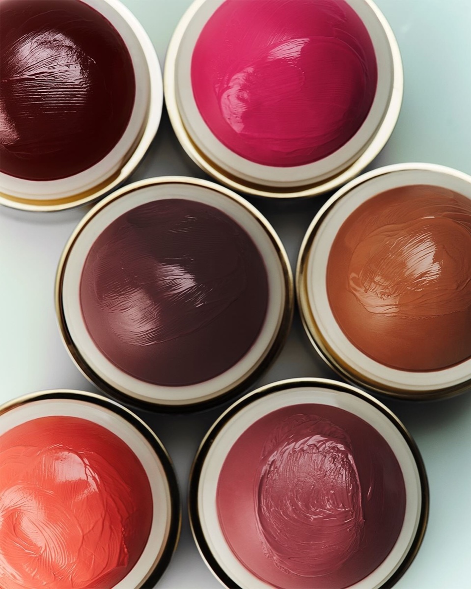 Six open Merit Flush Balm bullets seen from above in shades from deep wine to bright fuchsia and terracotta