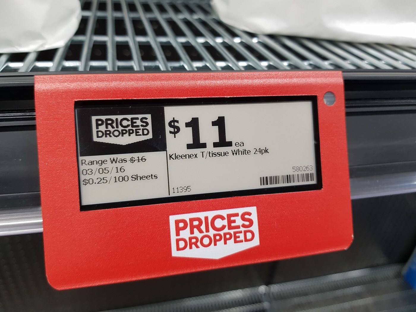 A red electronic shelf label on a supermarket rail showing eleven dollars each, with the previous range price of sixteen dollars struck through beside a dated line