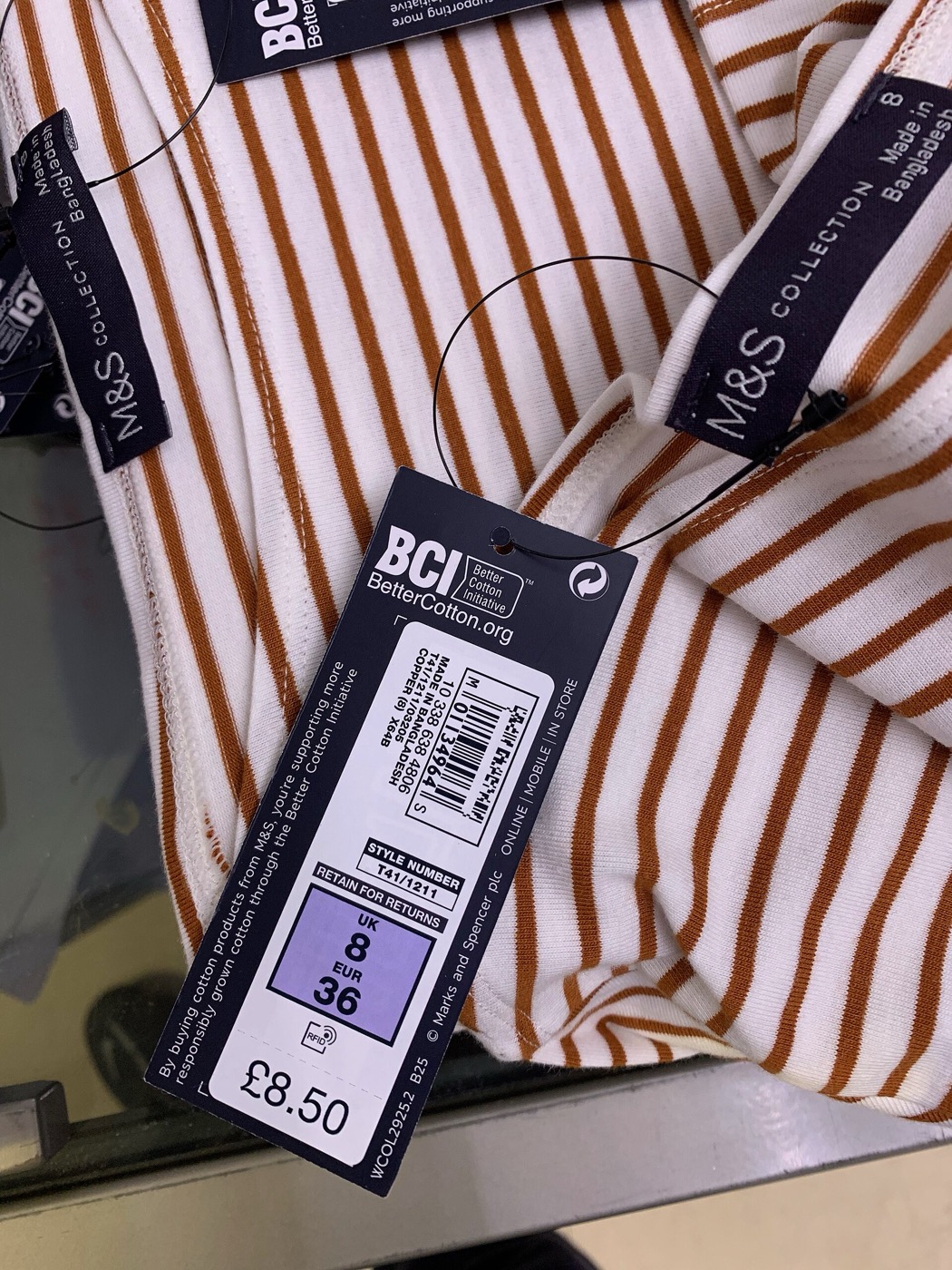 A navy M&S swing ticket hanging from a rust-and-cream striped top, printed with a UK 8 size box and a price of 8 pounds 50