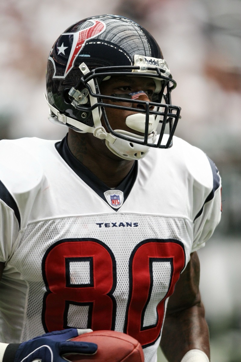 A Houston Texans player in helmet and white on-field jersey holding a football