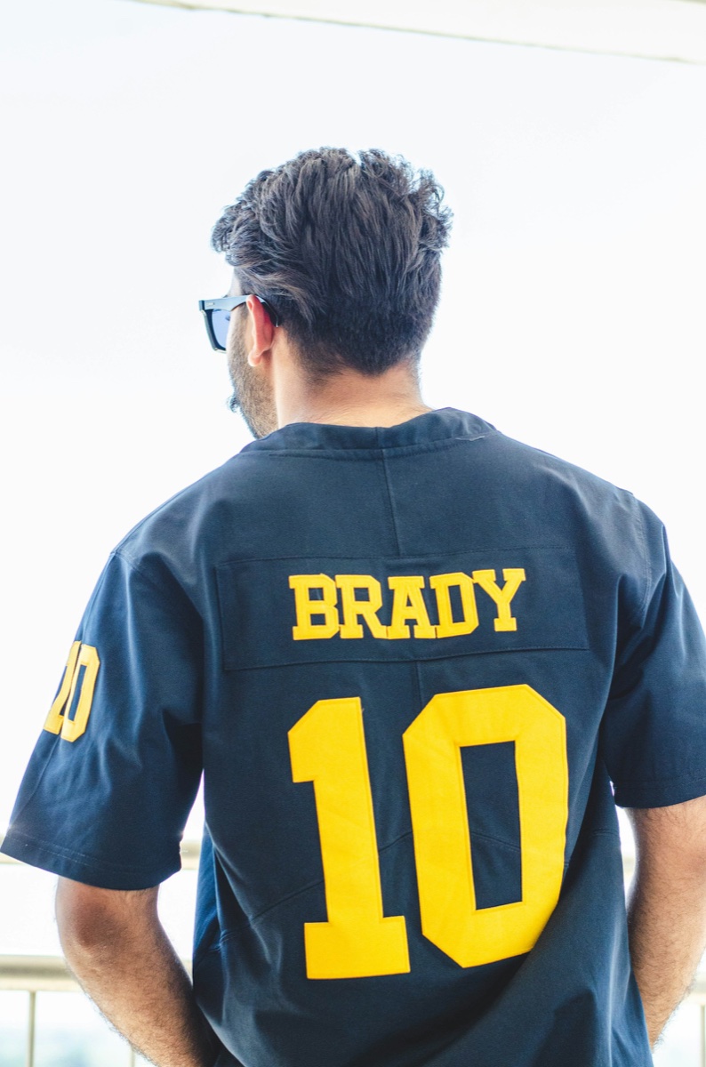 Back view of a man in a navy football jersey with stitched yellow tackle-twill name and number 10