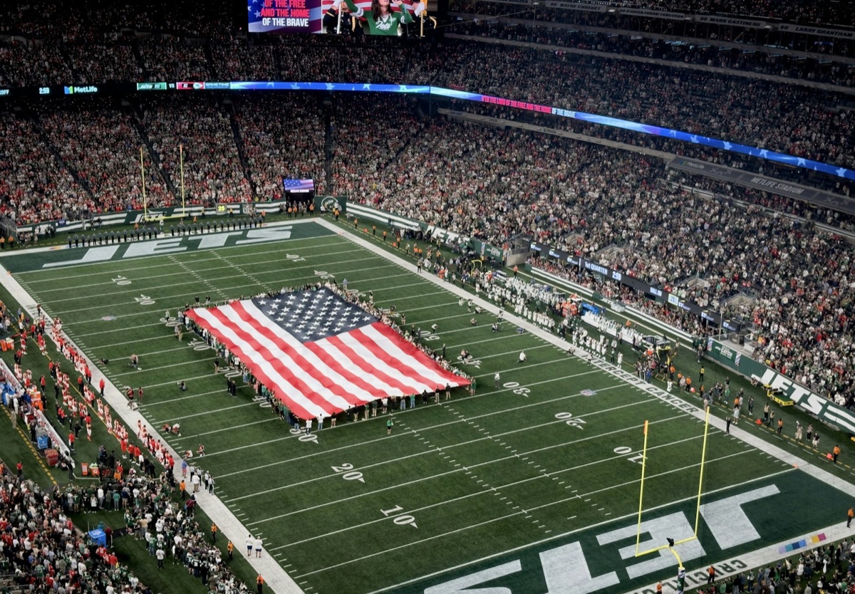 An American flag covering the field during the anthem before a New York Jets game in a packed MetLife Stadium