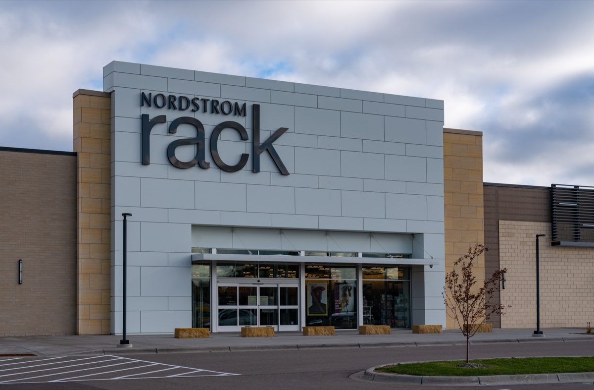 Nordstrom Rack storefront in Woodbury, Minnesota, with a pale blue facade and glass entry under a cloudy sky
