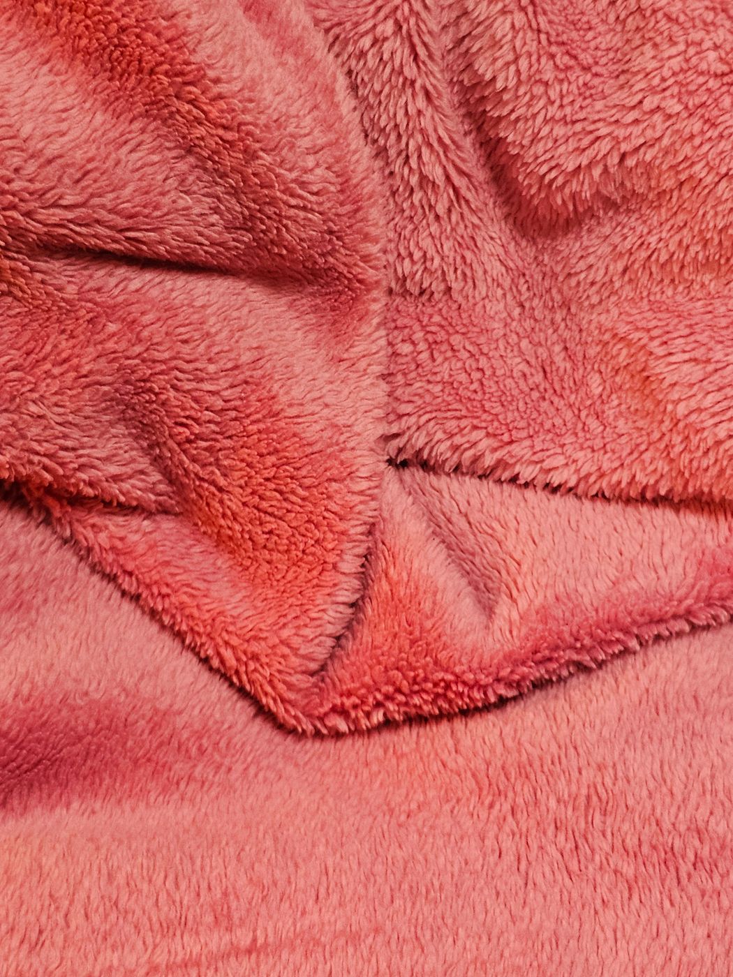 Close-up of soft pink plush pile fabric folded into low ridges