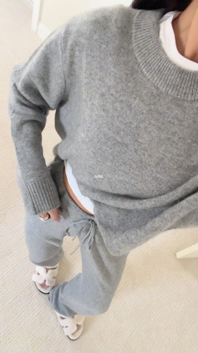 A heather grey cashmere crewneck worn with matching grey sweatpants and slippers, seen from above on a cream carpet