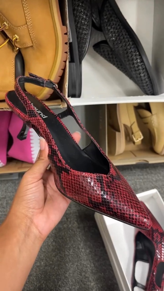 A red snakeskin slingback held up in the Rack shoe aisle; the insole reads Abound, one of Nordstrom's own off-price labels