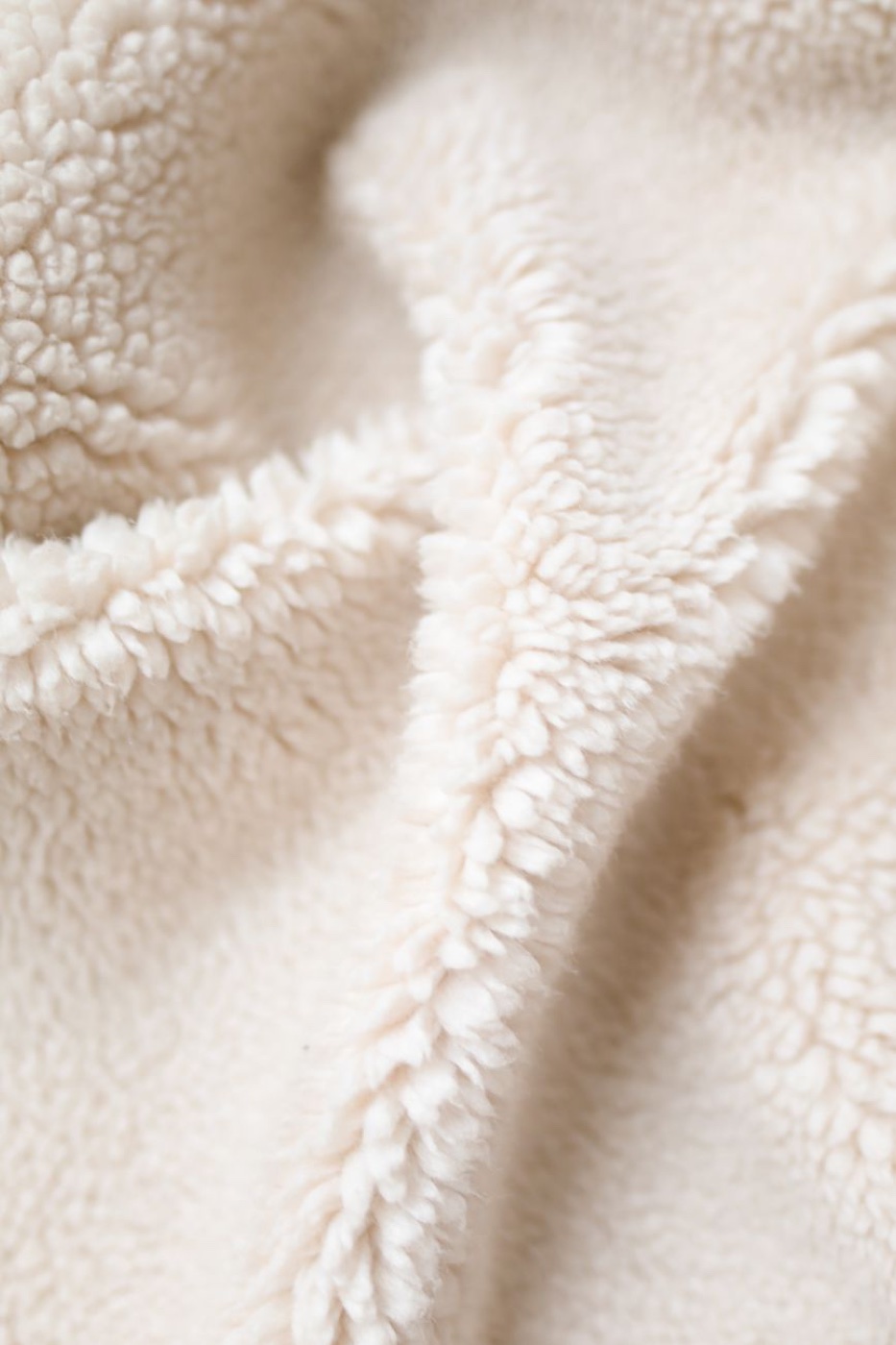Close-up of the looped pile surface of a cream fleece fabric, folded so the nap catches the light