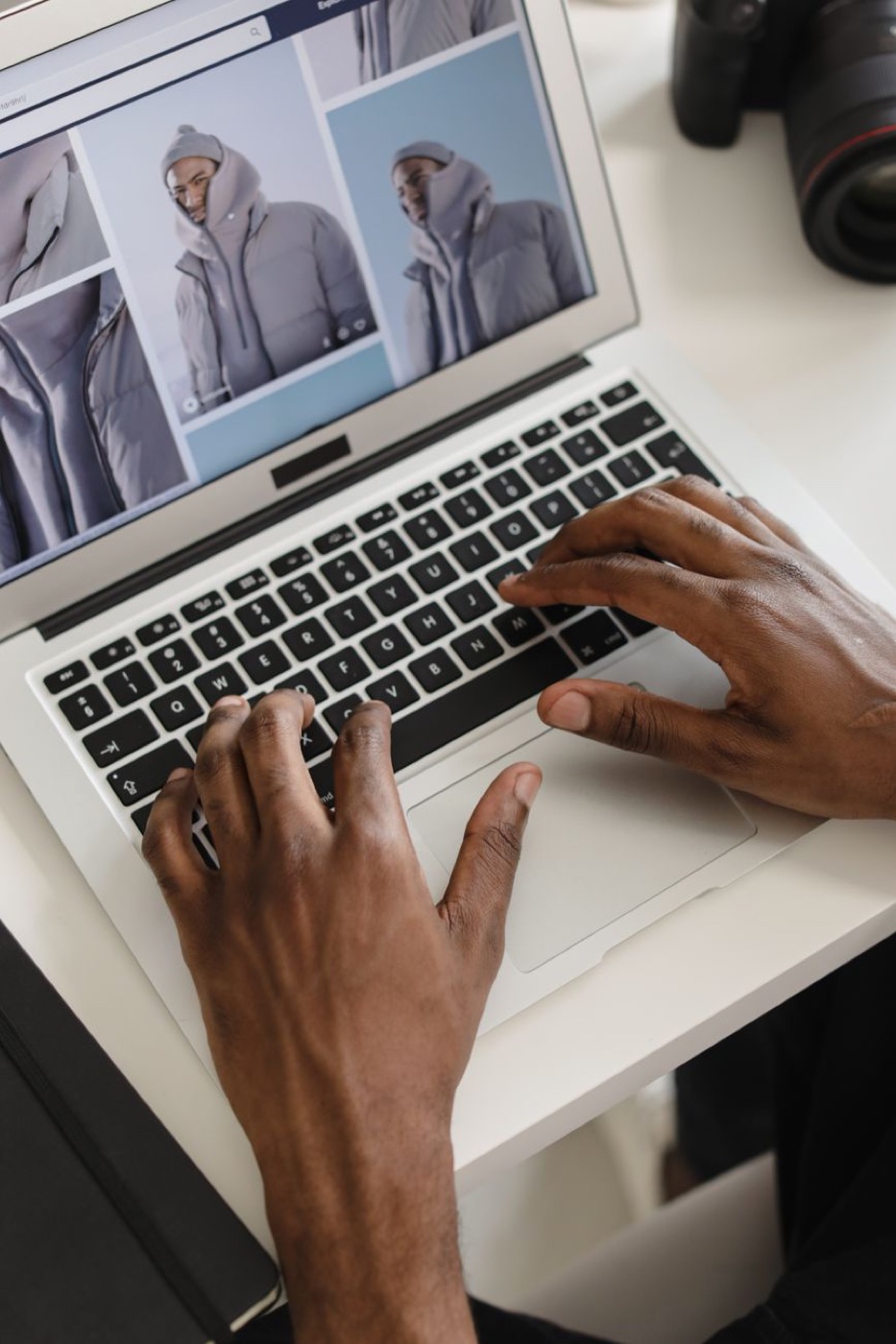Hands on a laptop keyboard, the screen showing a product listing with three photographs of the same grey puffer jacket