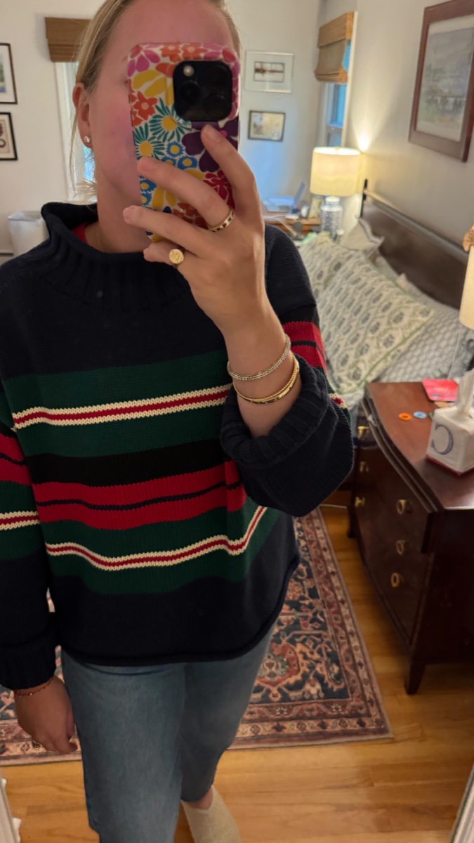 Mirror selfie of a navy rollneck sweater with green, red and cream stripes, worn with light jeans in a bedroom