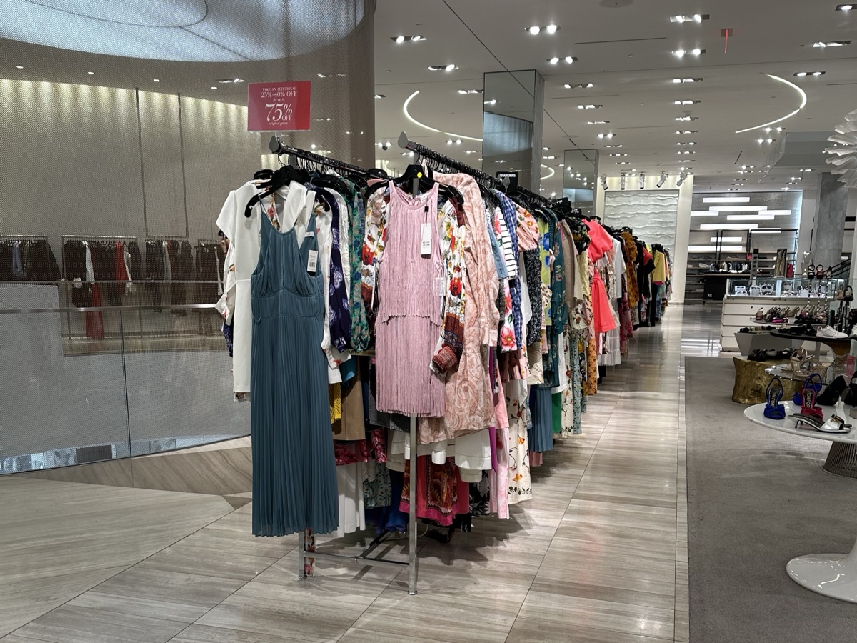 Clearance rack of dresses under a red 75% off sign inside Saks Fifth Avenue at Brickell City Centre in Miami
