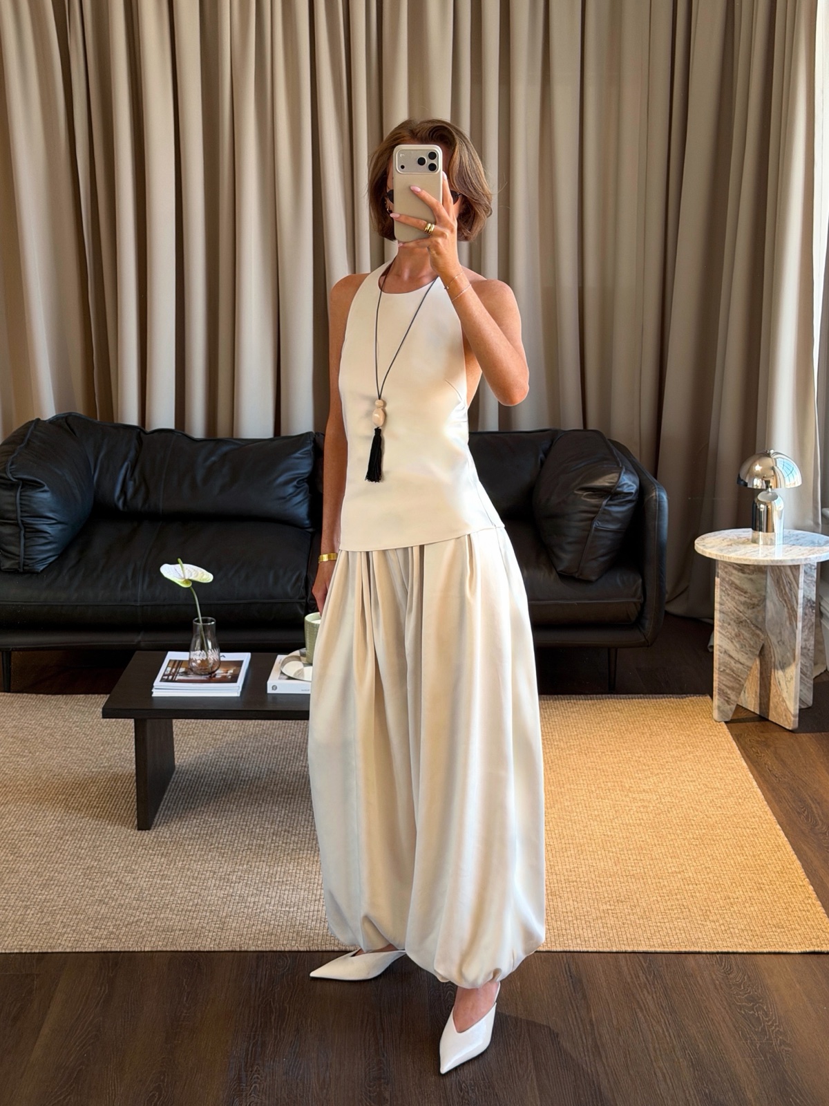 A mirror selfie of a cream satin co-ord with a halter top and bubble-hem trousers, styled with white heels in a living room
