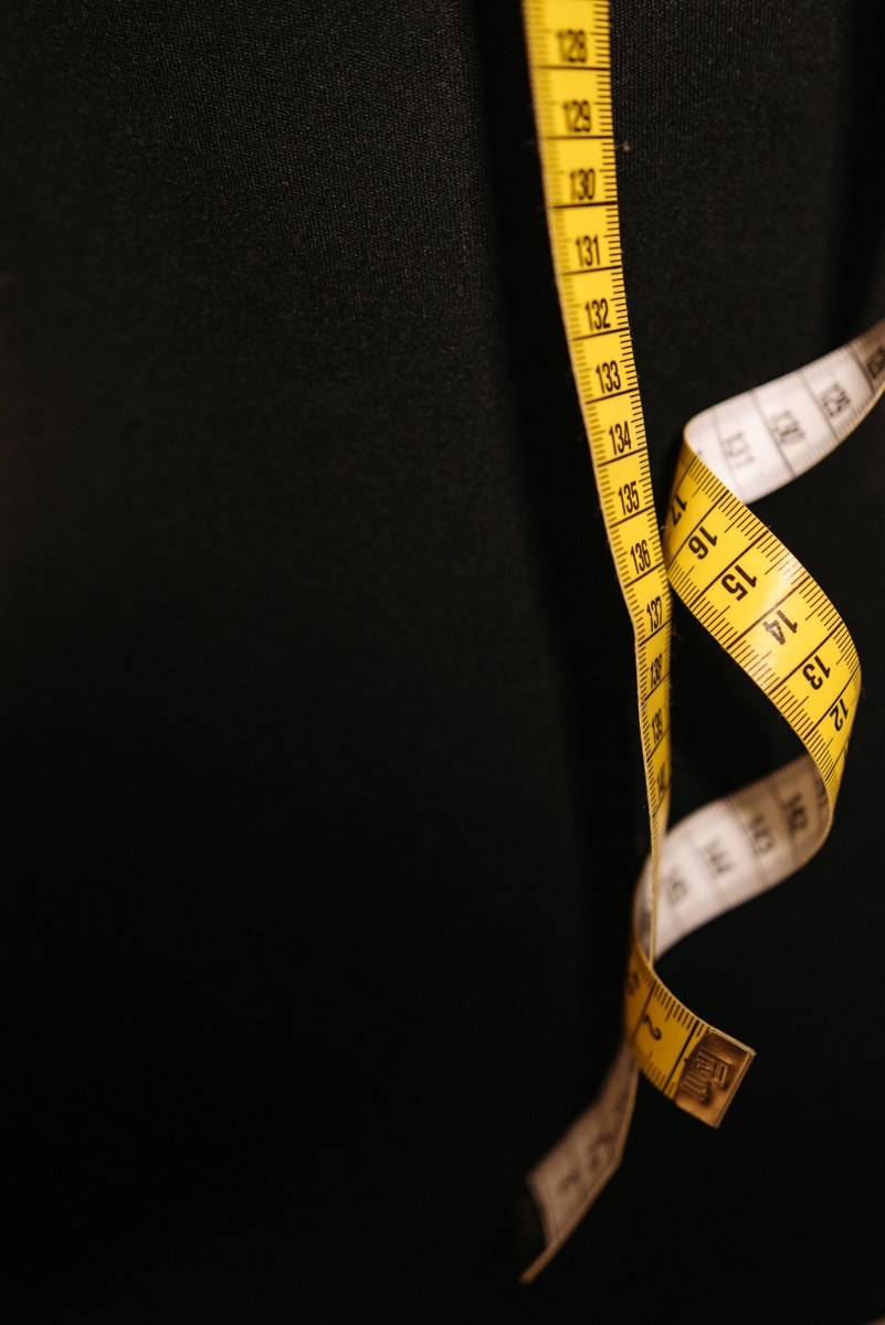 A yellow tailor's tape marked in centimetres draped over a dark garment