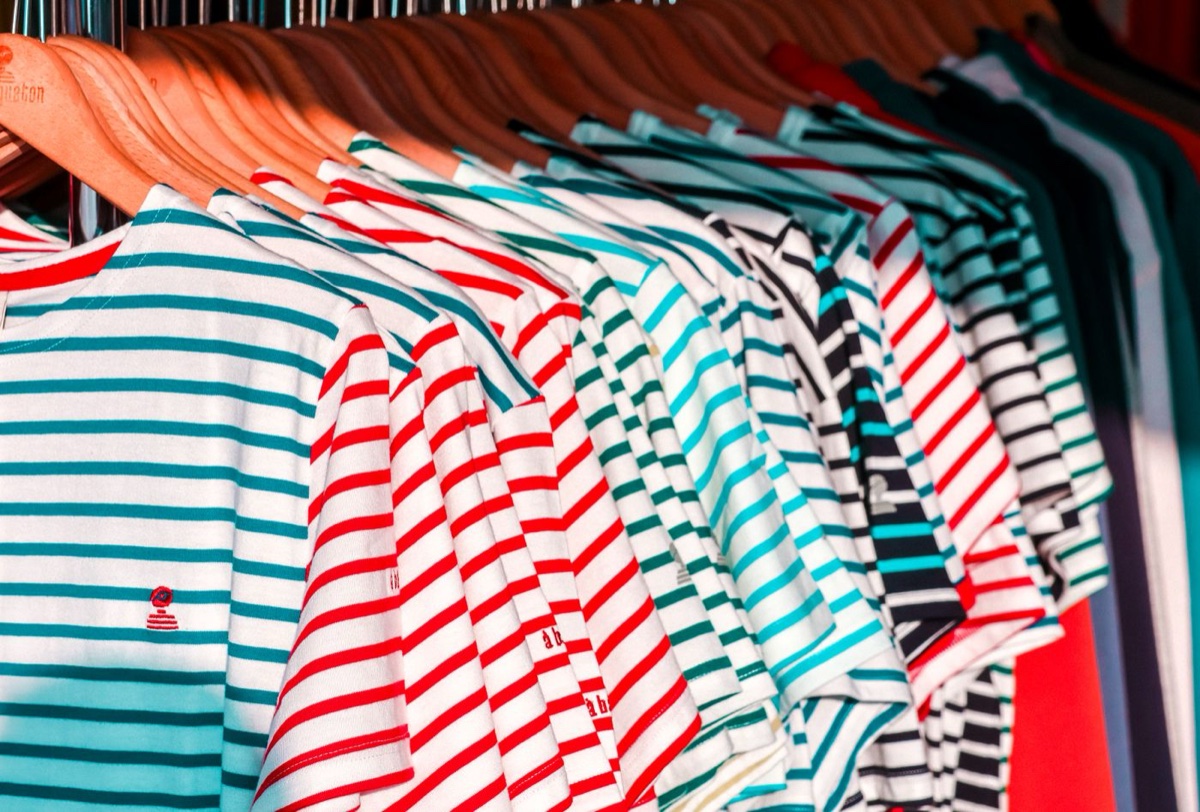 A close rack of Breton-striped cotton tees on wooden hangers, red, navy, teal and black stripes overlapping