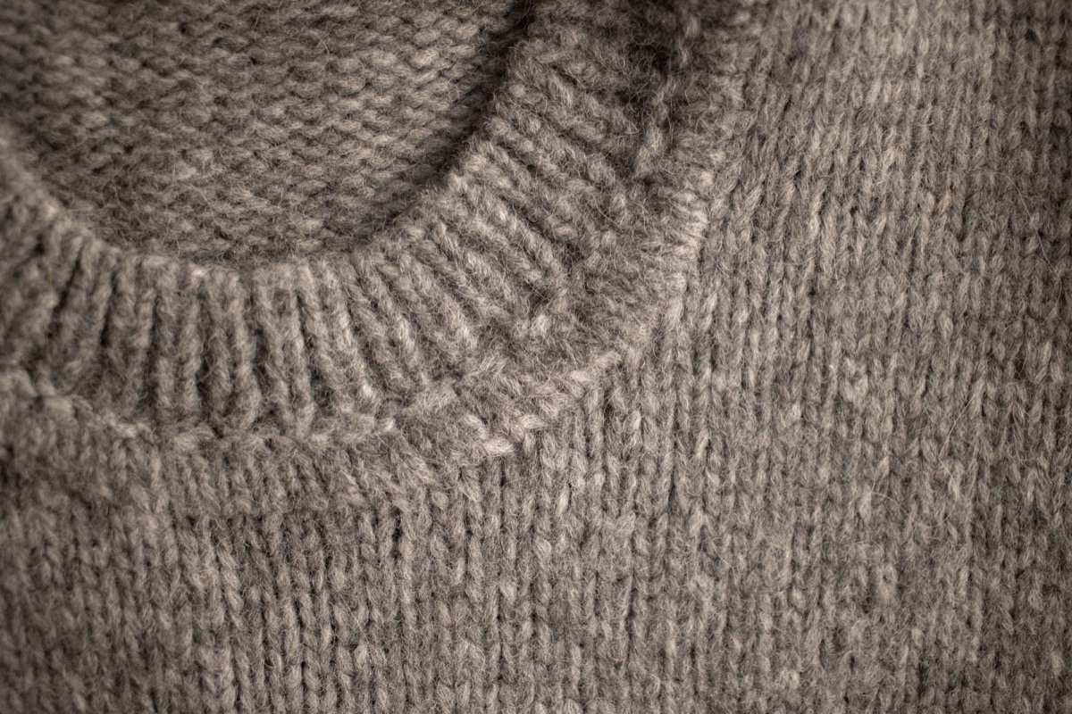 A close-up of a gray wool sweater collar with a visible layer of surface fuzz rising off the stitches