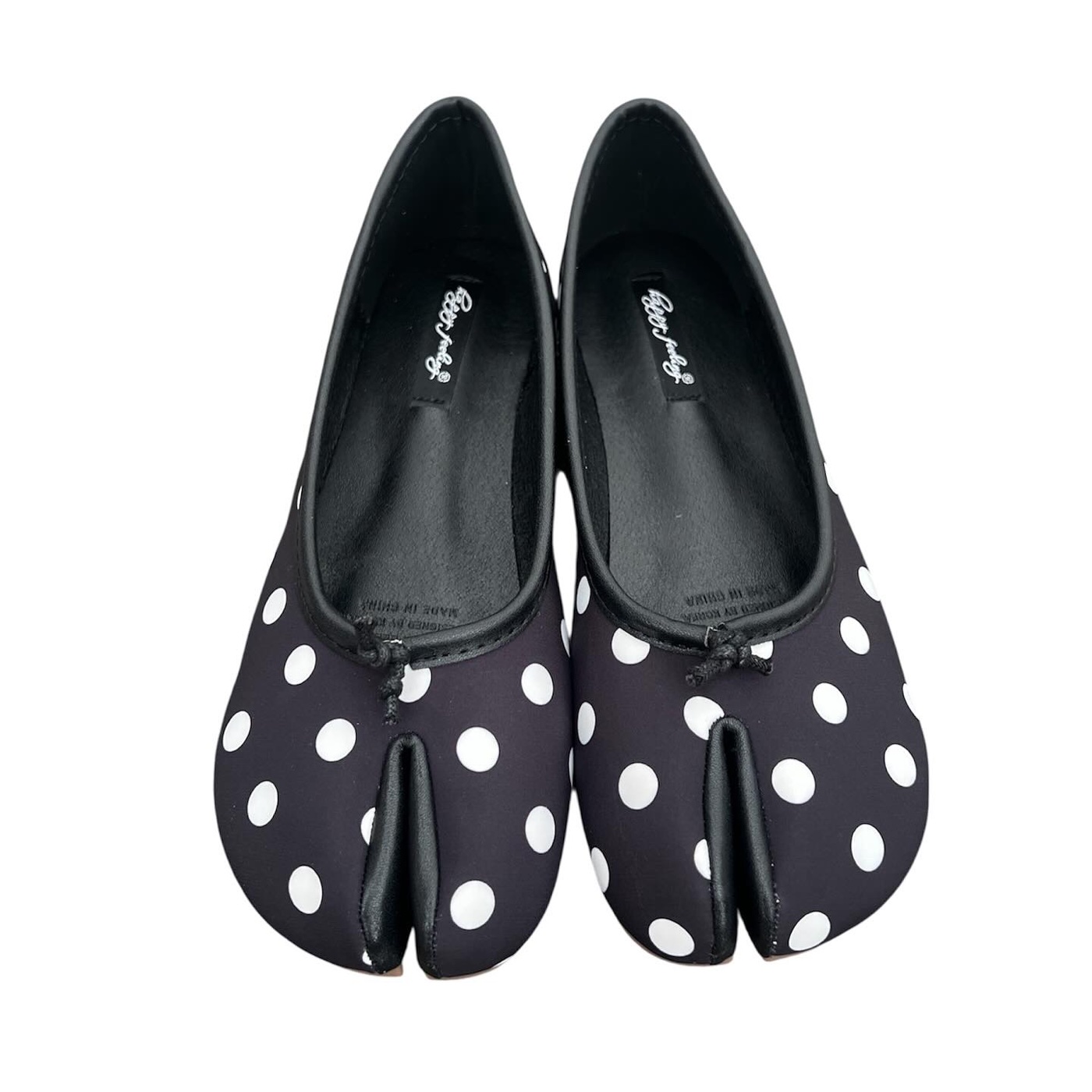 Pair of black split-toe ballet flats in white polka dot fabric, photographed from above on a white background, insole marked Made in China