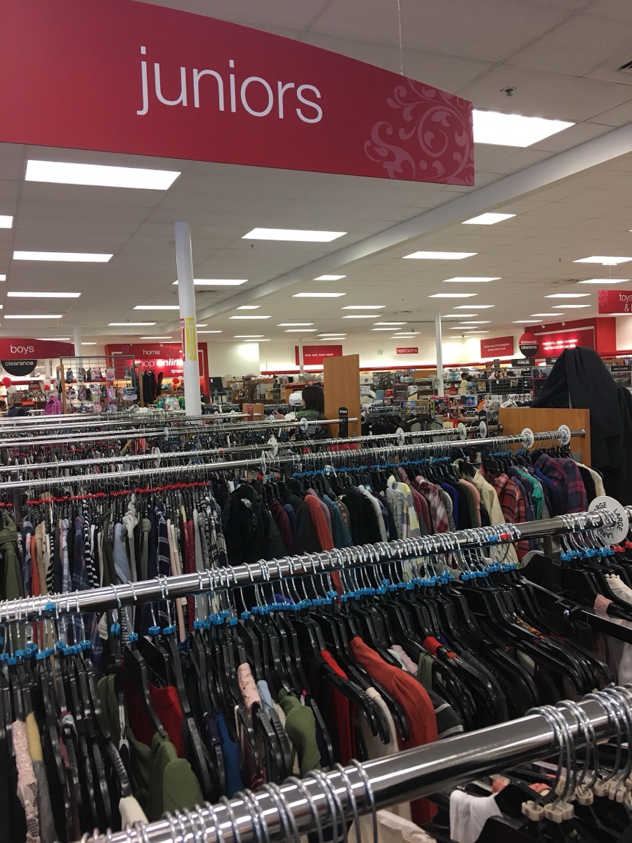 Rows of packed clothing racks under a red juniors section sign inside a T.J. Maxx store