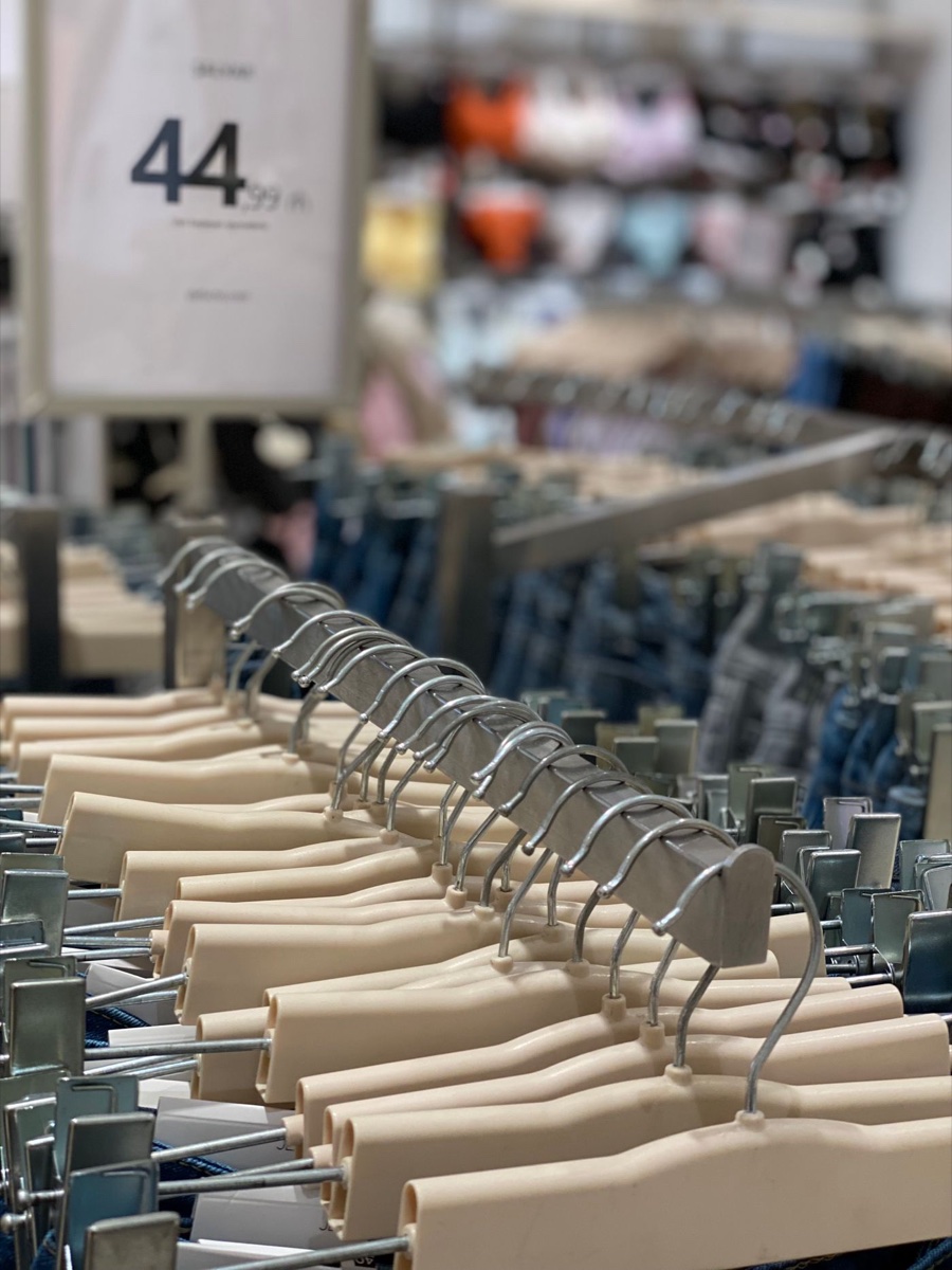 Rows of beige clip hangers holding jeans on a store rack, a 44.99 price sign standing above them
